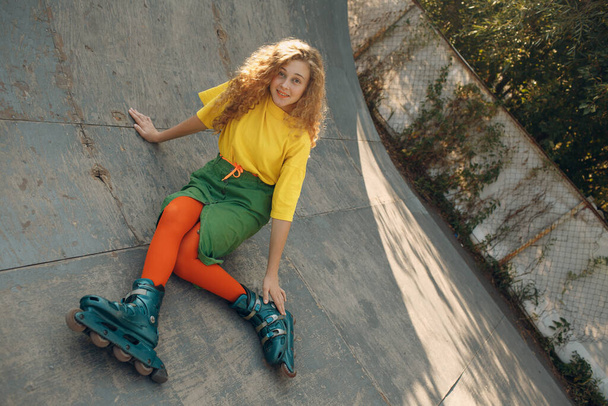Young woman girl in green and yellow clothes going roller skate - Фото, зображення