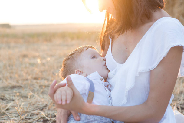 Beautiful happy mother breastfeeding her baby boy outdoor. - Valokuva, kuva