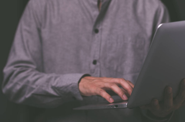 A standing man using a laptop computer - Фото, изображение