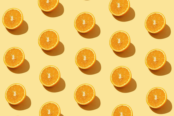 Modern pattern with orange slices on yellow background illuminated by bright summer sunlight - Pop art design minimal creative concept - Fresh fruits top view - Foto, Bild