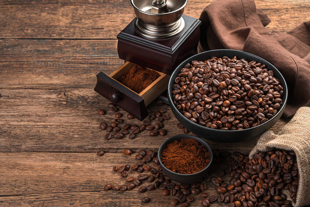 Kávébab, őrölt kávé és egy kávédaráló barna háttérrel. Oldalnézet fénymásoló felülettel. - Fotó, kép