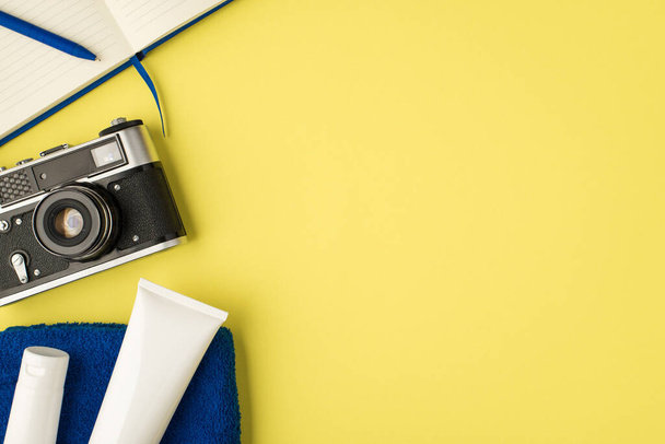 Top view kuva sininen suunnittelija kynä kamera ja kaksi valkoista kermapulloa pyyhkeellä eristetty keltainen tausta Copyspace - Valokuva, kuva