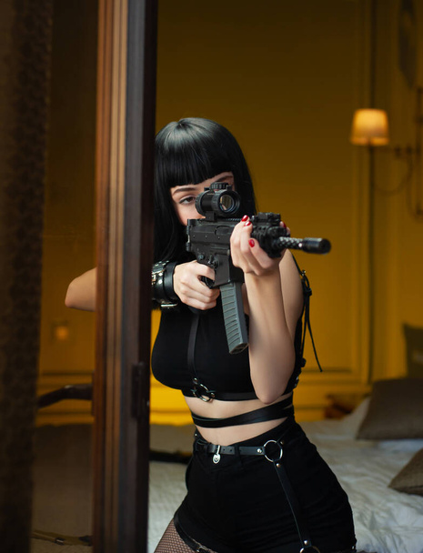 Женщина-киллер в отеле рядом с окном направляет автоматическую винтовку с телескопическим прицелом на жертву, совершившую убийство - Фото, изображение