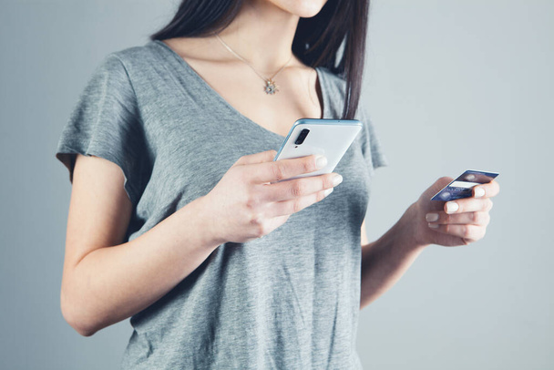 girl holding a phone and a bank card in her hands - Foto, Bild