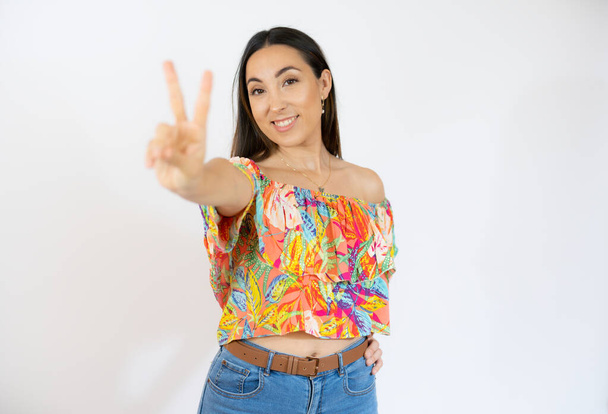 Young hispanic woman isolated showing victory sign and smiling broadly. - Photo, Image