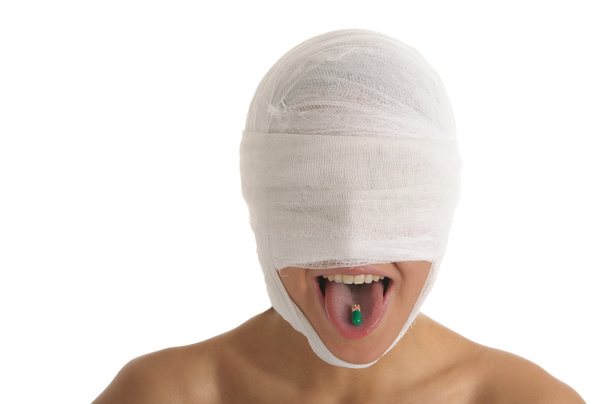 Mulher jovem com cabeça enfaixada com comprimido na língua isolada em branco
 - Foto, Imagem