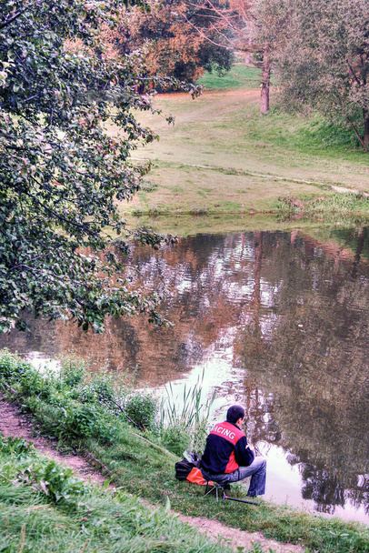 A young fisherman guest worker is fishing on a small pond in the park - Photo, image