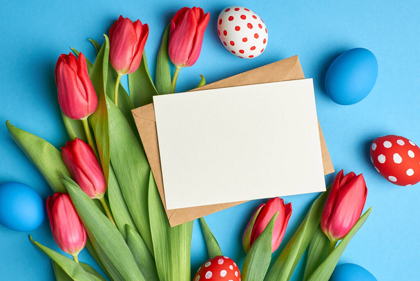 Easter holiday greeting card mockup with colored eggs and red tulip flowers on blue - Valokuva, kuva