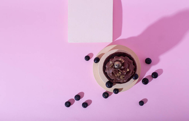 Gluten free cake with blueberry and carob. Homemade chocolate cake with raw berries on modern circle and square podiums on pink background. Creative food photo with shadows. Top view - Fotó, kép