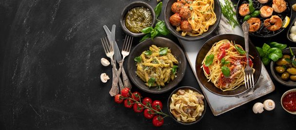 Assortment of Italian pasta with traditional sauces for dinner on dark background. Homemade food concept. Top view - Foto, imagen