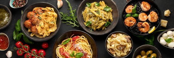 Assortment of Italian pasta with traditional sauces for dinner on dark background. Homemade food concept. Top view - 写真・画像