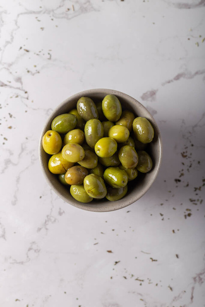 Olives vertes dans un bol sur fond de marbre. - Photo, image