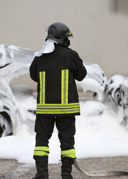 İtfaiyeci yangını söndürüyor kazadan sonra köpüklü hasarlı bir araba. - Fotoğraf, Görsel