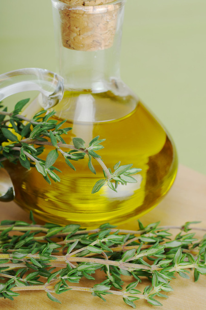 Свіжий чебрець гілочка з оливковою олією в скляній пляшці на дерев'яній дошці і зеленим килимком для столу (селективний фокус
) - Фото, зображення