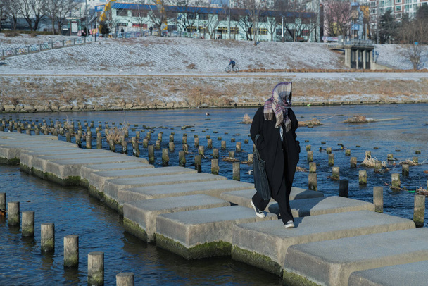 A person crossing stone bridge in cold weather - Zdjęcie, obraz