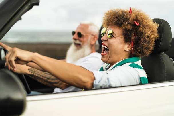Feliz pareja de personas mayores que se divierten conduciendo en un coche nuevo convertible - Personas maduras disfrutando del tiempo juntos durante las vacaciones de viaje por carretera - Estilo de vida anciano y cultura de viaje concepto de transporte - Foto, imagen