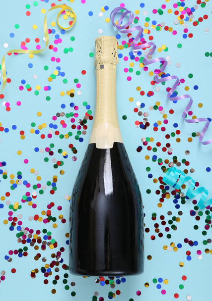 Butelka szampana i konfetti z serpentyną na niebieskim tle  - Zdjęcie, obraz