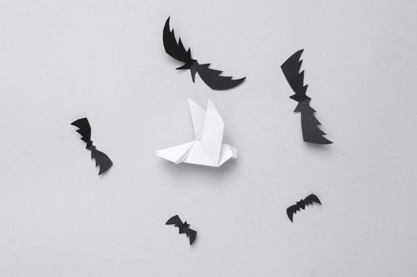 Light and darkness. Good and evil. Paper bats and dove on gray background - Photo, Image