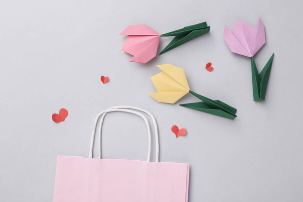 Bolsa de compras y corazones, tulipanes sobre un fondo gris. Compras de vacaciones, descuentos, venta, composición del día de San Valentín - Foto, Imagen