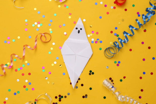 Origami Halloween duch s barevným stuhou s konfety na žlutém pozadí. Halloweenská oslava, zábava a strach. Horní pohled. Plocha - Fotografie, Obrázek
