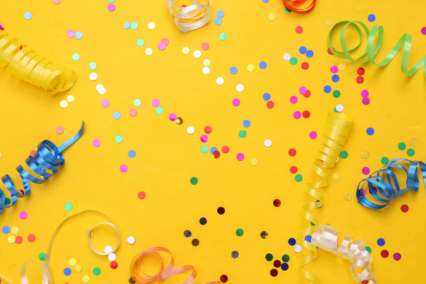 Colored streamer and confetti on yellow background. Holiday, birthday background - Фото, изображение