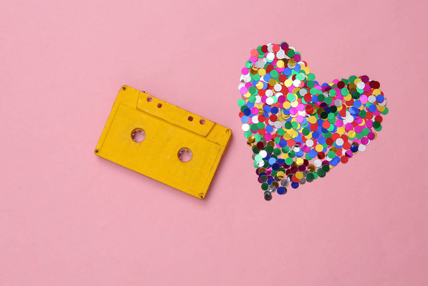 Audio cassette and heart shaped confetti on pink background - Φωτογραφία, εικόνα