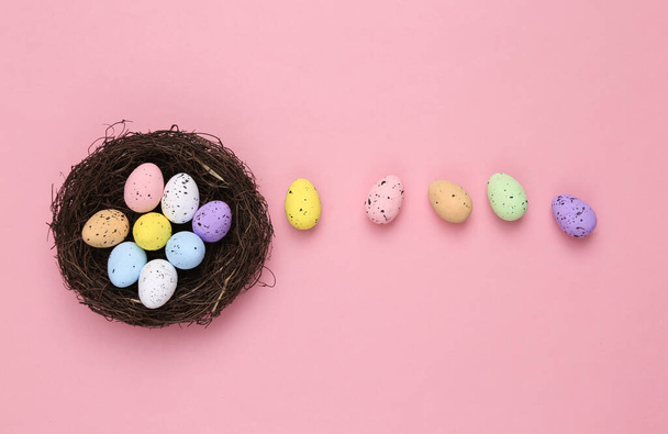 Nest with colored quail eggs on a pink background. Easter composition - Fotografie, Obrázek