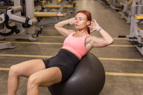 Fit kobieta trenuje mięśnie brzucha robi skręcanie na fitball. - Zdjęcie, obraz