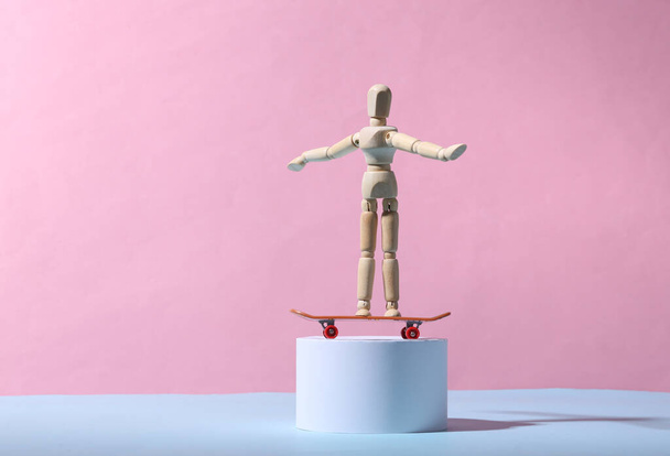 Wooden puppet with a skateboard on the stand. Blue-pink background. Minimalism - Fotografie, Obrázek