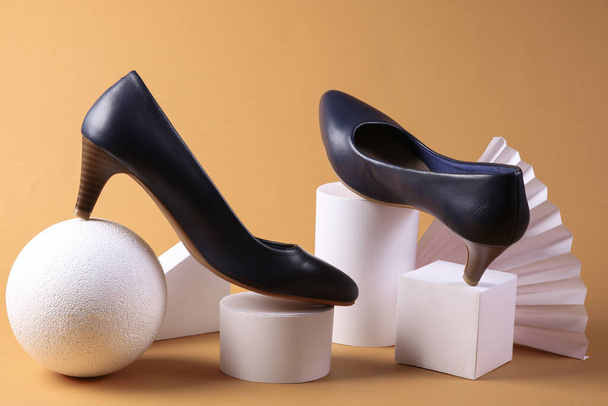 Fashion showcase. Leather shoes with heels and geometric shapes on a beige background  - Photo, Image