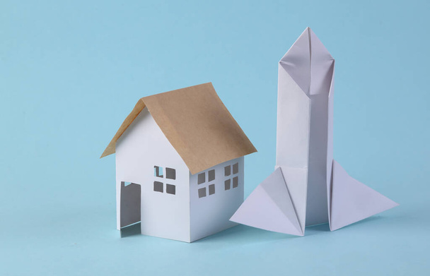 House figurine and paper rocket on a blue background. Colonization of other planets, startup concept  - Photo, Image