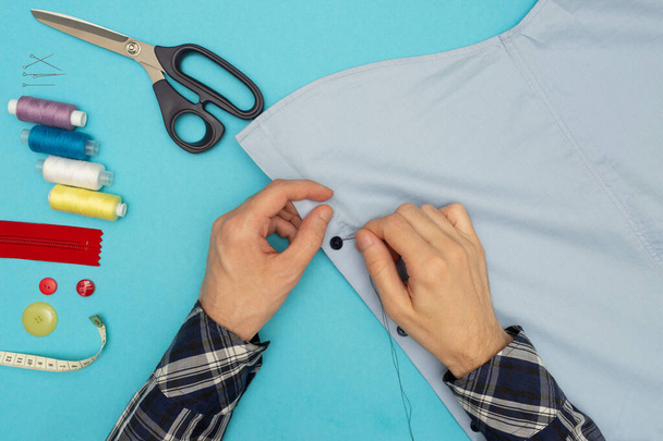 Tailor sews. Mens hands are sewing on a button. Clothing sewing and repair. Creative development. Learning new things - 写真・画像