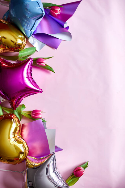 Style de pose plat de ballons de couleur avec décoration florale de tulipes sur fond rose. Anniversaire, fête ou concept de fête, espace de copie pour le texte. - Photo, image