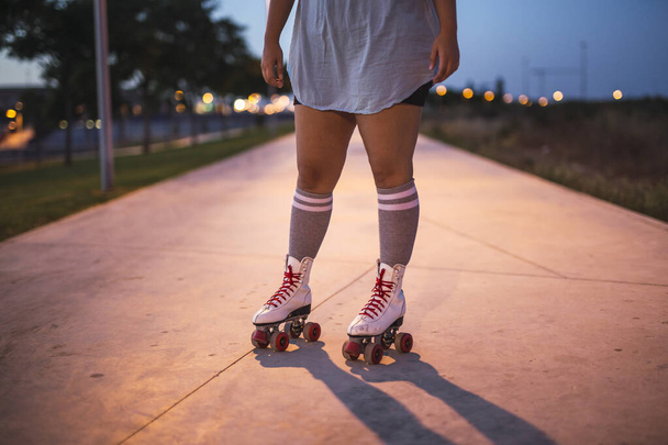A closeup shot of a woman wearing white roller skates on a blurred background - Foto, Bild