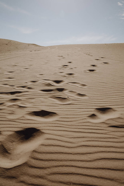 A vertical shot of footprints on sand dunes in a desert - Fotografie, Obrázek