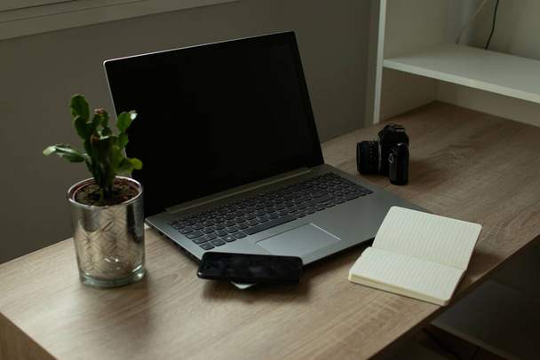 A laptop, an open notebook, a cellphone, and a plant on an office table - 写真・画像