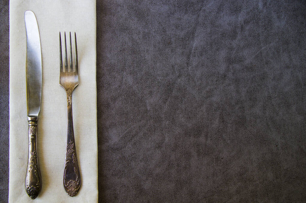 Gümüş çatalın üst görüntüsü ve masanın üzerindeki peçetede bir bıçak. - Fotoğraf, Görsel