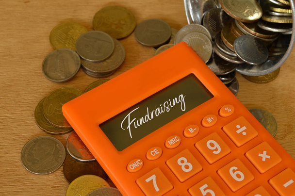 Stos monet i kalkulator napisany z FUNDRAISING. Koncepcja finansowa. - Zdjęcie, obraz