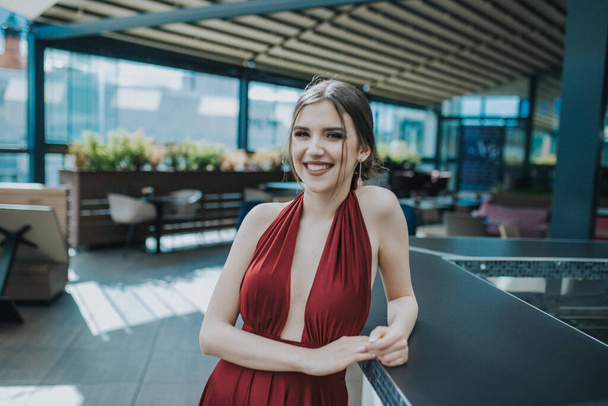 A closeup shot of an attractive woman with a red sexy evening dress on the outdoor cafe - Photo, Image