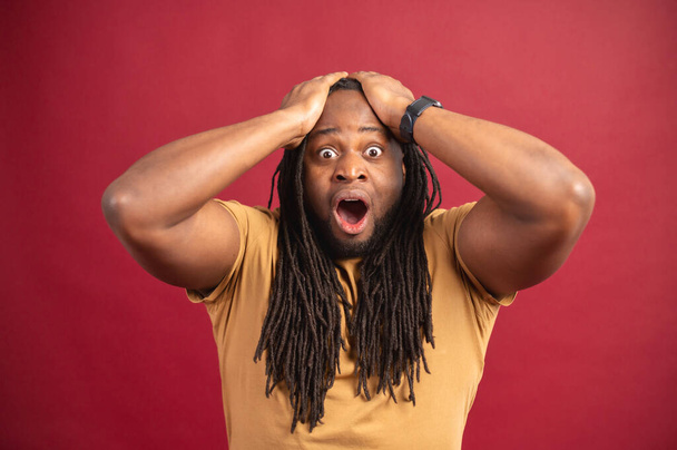 Shocked African-American guy isolated on red - Фото, изображение