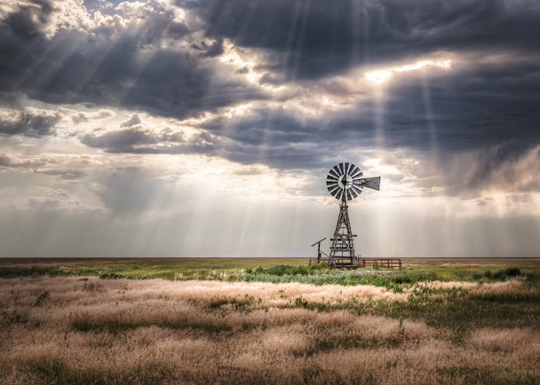 Old windmill in a rural meadow setting on a farm with storm clouds overhead. The clouds look ominous. - Photo, Image