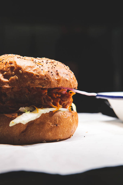 A studio shot of a juicy meat burger on white paper - Foto, imagen
