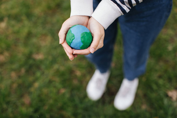 Female hands holding Earth in hands against green spring background. - Photo, Image