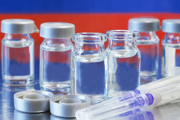 syringes and bottles of vaccine on background of the Russian Federation flag, vaccine against coronavirus, closeup - Photo, Image