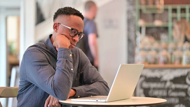 Африканський чоловік думає і працює на ноутбуці в кафе
  - Фото, зображення