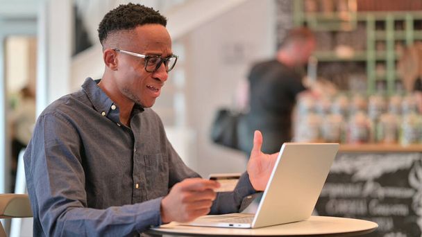 Online fizetési hiba a laptopon afrikai férfi a Cafe  - Fotó, kép