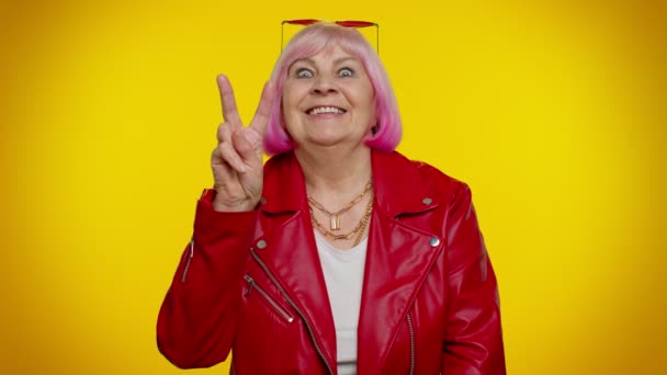 Reife Großmutter zeigt Siegeszeichen, hofft auf Erfolg und Sieg, macht Friedensgeste, lächelt - Filmmaterial, Video