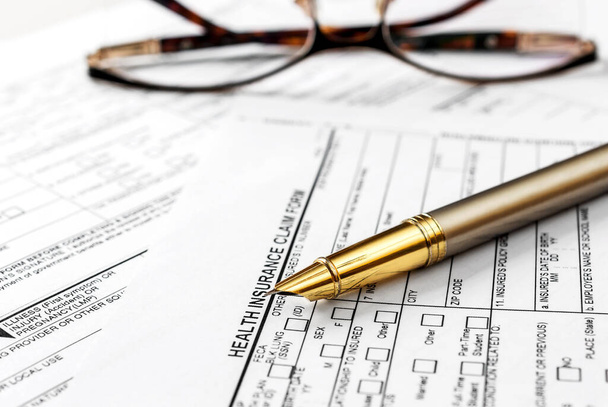 Pen with eyeglasses on health insurance claim form. - Fotó, kép