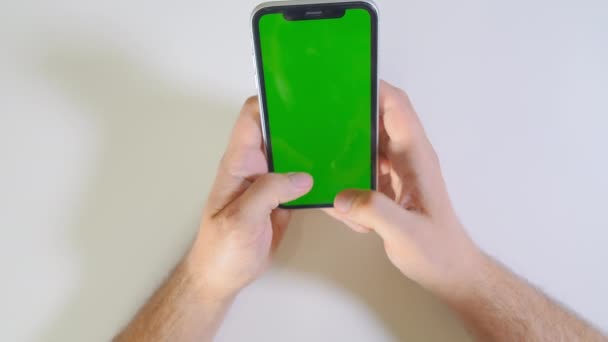 Vista dall'alto della mano dell'uomo utilizzando lo smartphone su sfondo bianco - Filmati, video
