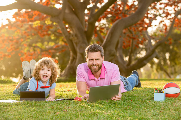 Outdoor education. Son with father watching lesson on laptop outdoors. Childhood and parenthood kids concept. - Foto, immagini